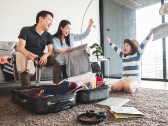 Mandare i bambini in colonia – famiglia prepara insieme la valigia per il campo estivo.