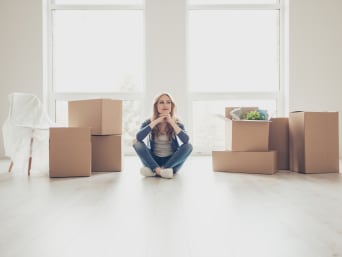 Une femme assise à côté de ses cartons de déménagement, après avoir emménagé dans son nouvel appartement.