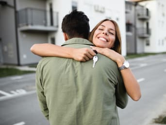 Frau umarmt ihren Partner bei der Wohnungsübergabe.