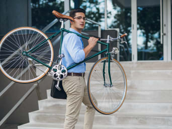 Op de fiets naar het werk: een man die zijn fiets de trap op draagt.
