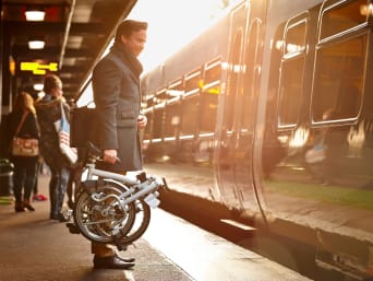 Mann nutzt den Zug und sein Faltrad, um zur Arbeit zu pendeln.