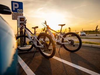 E-Bike: Elektrofahrräder stehen auf einem Parkplatz an einer Ladesäule.