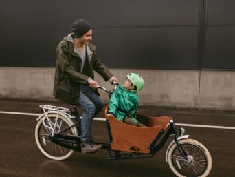 Cargobike: Vater nimmt seinen Sohn im Lastenrad mit.