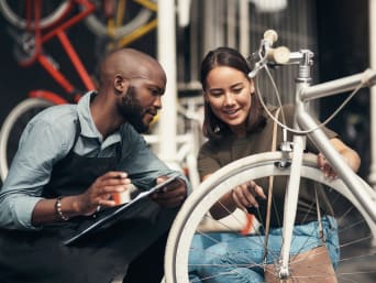 Comprare una bici usata: una cliente firma un contratto di vendita assieme a un rivenditore.