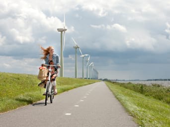 De Windmolenroute – Fietser met wind in het haar en windmolens op de achtergrond.