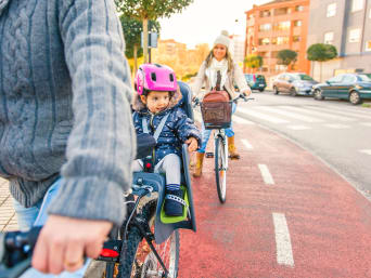 Kindersitz für Fahrrad: Kind sitzt bei einer Fahrt durch die Stadt im Kinderfahrradsitz. 