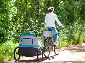 Fahrradanhänger für Kinder: Frau unternimmt eine Radtour mit Fahrradanhänger. 