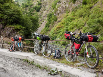 Radurlaub: Fahrräder mit Lenker-, Rahmen- und Satteltaschen lehnen an einem Brückengeländer.