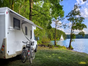 Mazurskie trasy rowerowe – kamper z rowerami parkujący nad jeziorem.