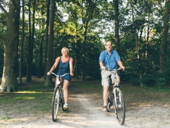 Fietsen door Noord-Brabant: Twee ouderen fietsen door een bos.