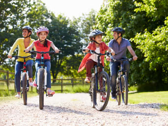 Velotouren Zürich: Junge Familie fährt mit dem Velo durch einen Park.