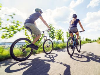 Velowege Zug: Junges Paar fährt mit ihren Mountainbikes an Weinbergen vorbei.