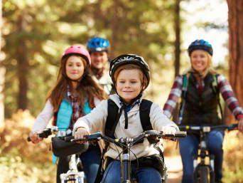 Seguridad vial en bicicleta para niños: una familia hace una excursión en bici por el monte.