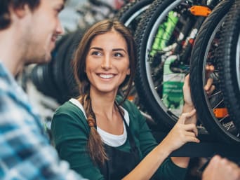 Seguridad en la bicicleta: una joven recibe asesoramiento en una tienda de bicicletas.