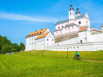 Szlak rowerowy wokół jeziora Wigry: rowerzysta zmierza w kierunku Pokamedulskiego Zespołu Klasztornego w Wigrach. Szlak rowerowy wokół jeziora Wigry: rowerzysta zmierza w kierunku Pokamedulskiego Zespołu Klasztornego w Wigrach.