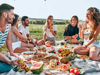 Picknick-Ideen: Gruppe von Freunden picknickt gemeinsam auf einer Wiese.