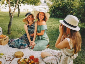 Modische Picknick-Outfits: Eine Gruppe von Freundinnen in Sommerkleidern. 