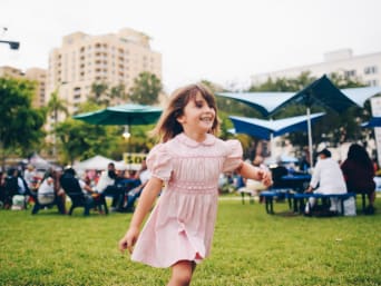 Festival en famille : une petite fille court sur la pelouse lors d’un festival pour enfant.