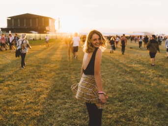 A young woman walking over a field at a festival.