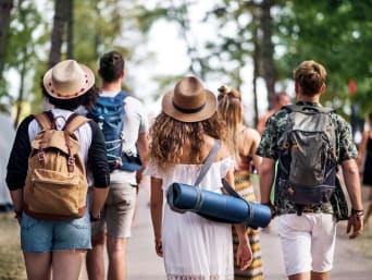 Návštěvníci letního filmového festivalu s batohy na cestě do kempu.