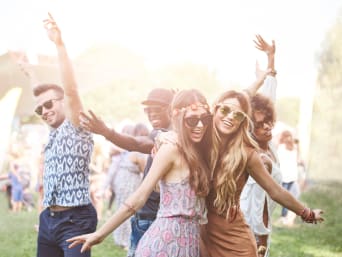Friends wearing boho outfits and dancing at a Festival.