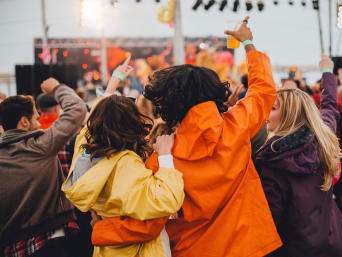 Festival bajo la lluvia: varios asistentes con chubasquero se lo pasan bien en un festival.