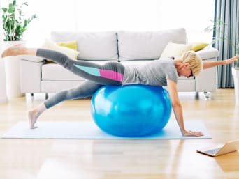 Frau trainiert zuhause mit einem Gymnastikball.