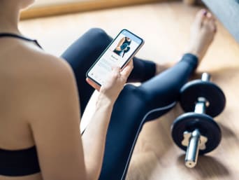 Zajęcia fitness online: dziewczyna ogląda filmik treningowy w aplikacji do fitnessu.