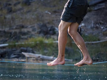 Slackline – mężczyzna balansuje na linie nad wodą.