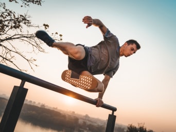Un hombre que practica parkour salta por encima de una barandilla.