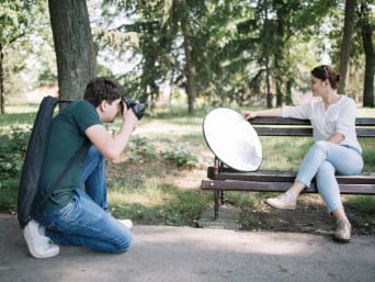 Fotografia portretowa bez tajemnic – fotograf używa blendy fotograficznej podczas sesji w parku.