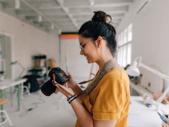 Fotografieren lernen – Frau überprüft ihre Kameraeinstellungen.