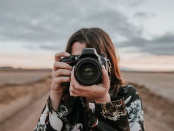 Cómo hacer mejores fotos: una mujer toma una foto con su cámara.