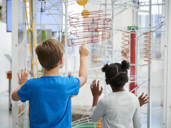 Musei per bambini – Bambini davanti a un esperimento in un museo di scienza.