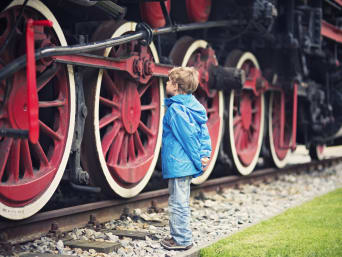Warum ist Geschichte wichtig – Kind steht vor einer historischen Eisenbahn.