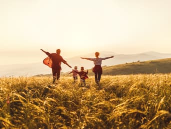 Ausflugsziele mit Kindern – Familie läuft gemeinsam über ein Feld bei Sonnenuntergang.
