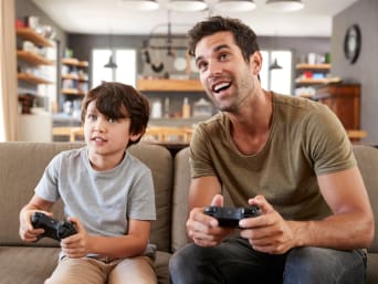 Gry komputerowe dla dzieci – ojciec i syn grają na konsoli.