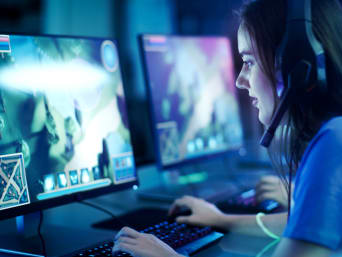 Kontrola rodzicielska dla bezpieczeństwa młodych graczy: dziewczyna w słuchawkach gra w grę przy komputerze. 