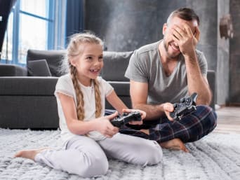 Un père et sa fille devant un écran en train de jouer à un jeu vidéo