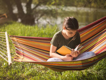 Une jeune fille lit un livre sur un hamac