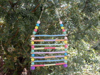 Kreatives Basteln für den Garten: Fertiges Windspiel hängt an Baum.