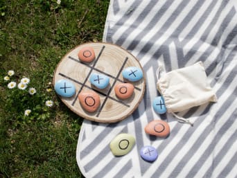 Czym zająć dziecko w ogrodzie: gra w kółko i krzyżyk wykonana z pomalowanych kamieni.