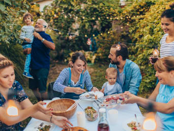 Co na zahradní párty: Rodina sedí na zahradě kolem stolu.