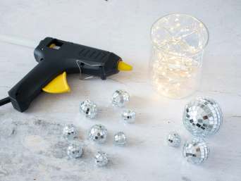 18. Geburtstag Tischdeko: Heißklebepistole, Vase und Mini-Discokugeln liegen auf einem Tisch. 18. Geburtstag Tischdeko: Heißklebepistole, Vase und Mini-Discokugeln liegen auf einem Tisch.