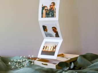 Geschenkideen für die beste Freundin: Eine Fotobox mit gemeinsamen Fotos von Freunden liegt auf einem Tisch. Geschenkideen für die beste Freundin: Eine Fotobox mit gemeinsamen Fotos von Freunden liegt auf einem Tisch.