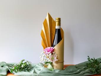 Geschenk für Papa basteln: Eine liebevoll verpackte Weinflasche steht auf einem Tisch. Geschenk für Papa basteln: Eine liebevoll verpackte Weinflasche steht auf einem Tisch.