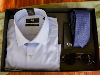 Geschenkideen Papa: Geschenkbox mit einem Hemd, Krawatte und Sonnenbrille liegt auf einem Tisch. Geschenkideen Papa: Geschenkbox mit einem Hemd, Krawatte und Sonnenbrille liegt auf einem Tisch.