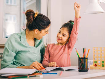 Come far fare i compiti: madre e figlia gioiscono dopo che la bambina ha finito di fare i compiti scolastici.