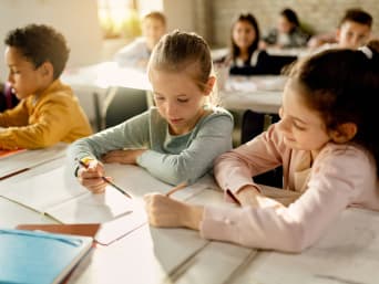 Kompetenzen Grundschule – Schülerin hilft einer Klassenkameradin im Unterricht
