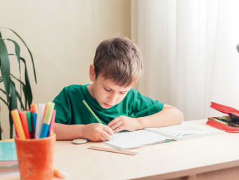 Dovednosti předškoláka – žák si u stolu dělá domácí úkoly.